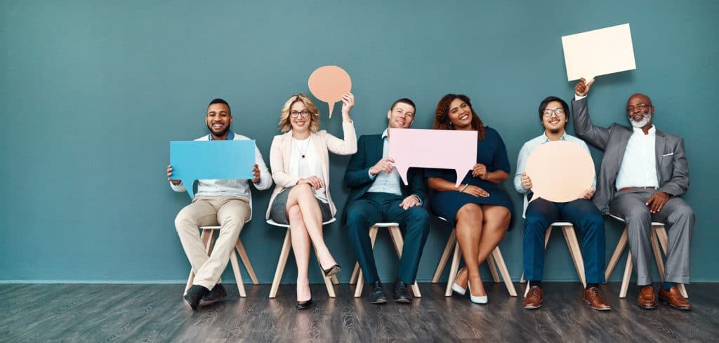 Let’s start a conversation Shot portrait of a diverse group of businesspeople holding up speech bubbles while they wait in line