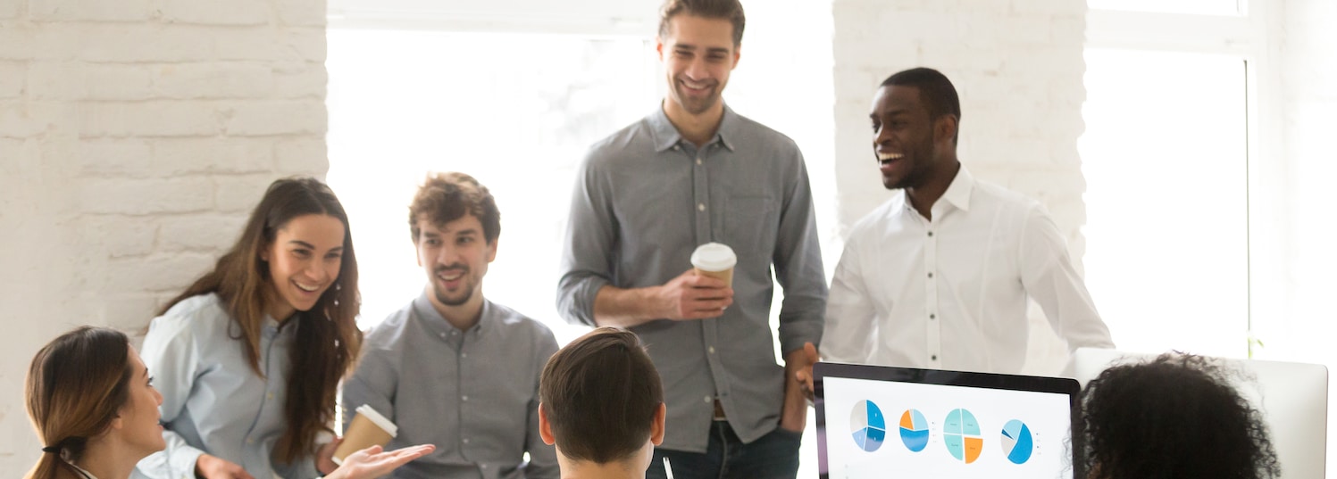 Smiling happy multiracial colleagues laughing together during coffee break, diverse corporate friendly staff team having fun chatting in coworking, mentors and interns enjoying talk in shared office