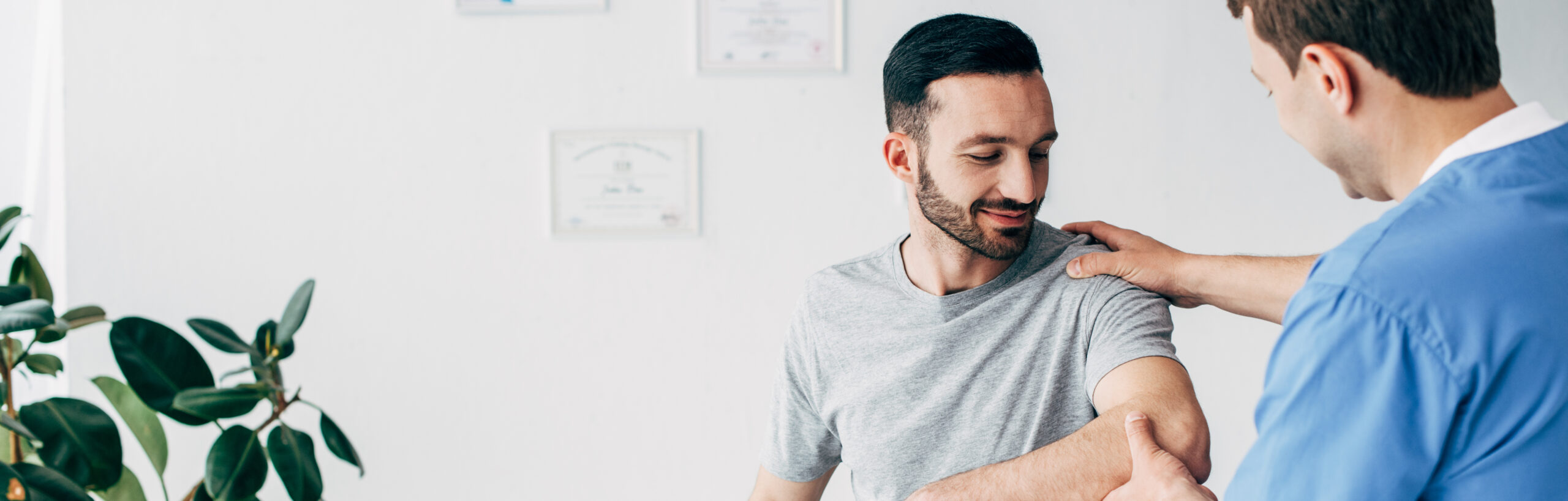 panoramic shot of chiropractor massaging arm of patient in hospital with copy space